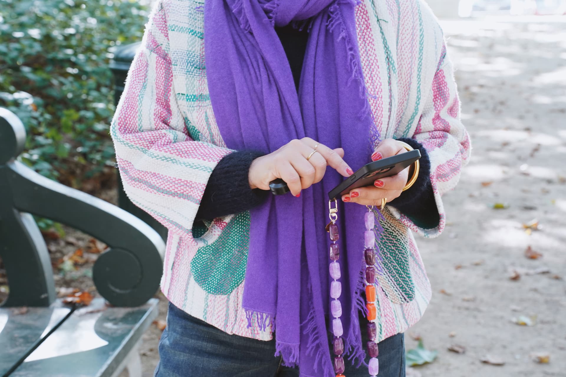 Détail : poncho rayé, écharpe violette et bijou de téléphone