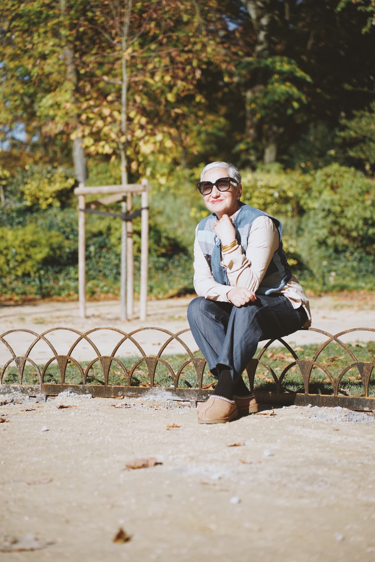 Accroupie sur la bordure du parterre, gilet patchwork et bottines beiges