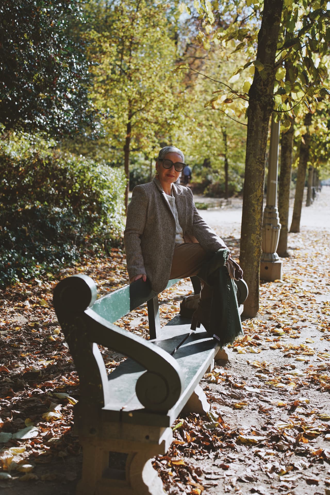 Sur un banc de l'allée, blazer en tweed et écharpe verte