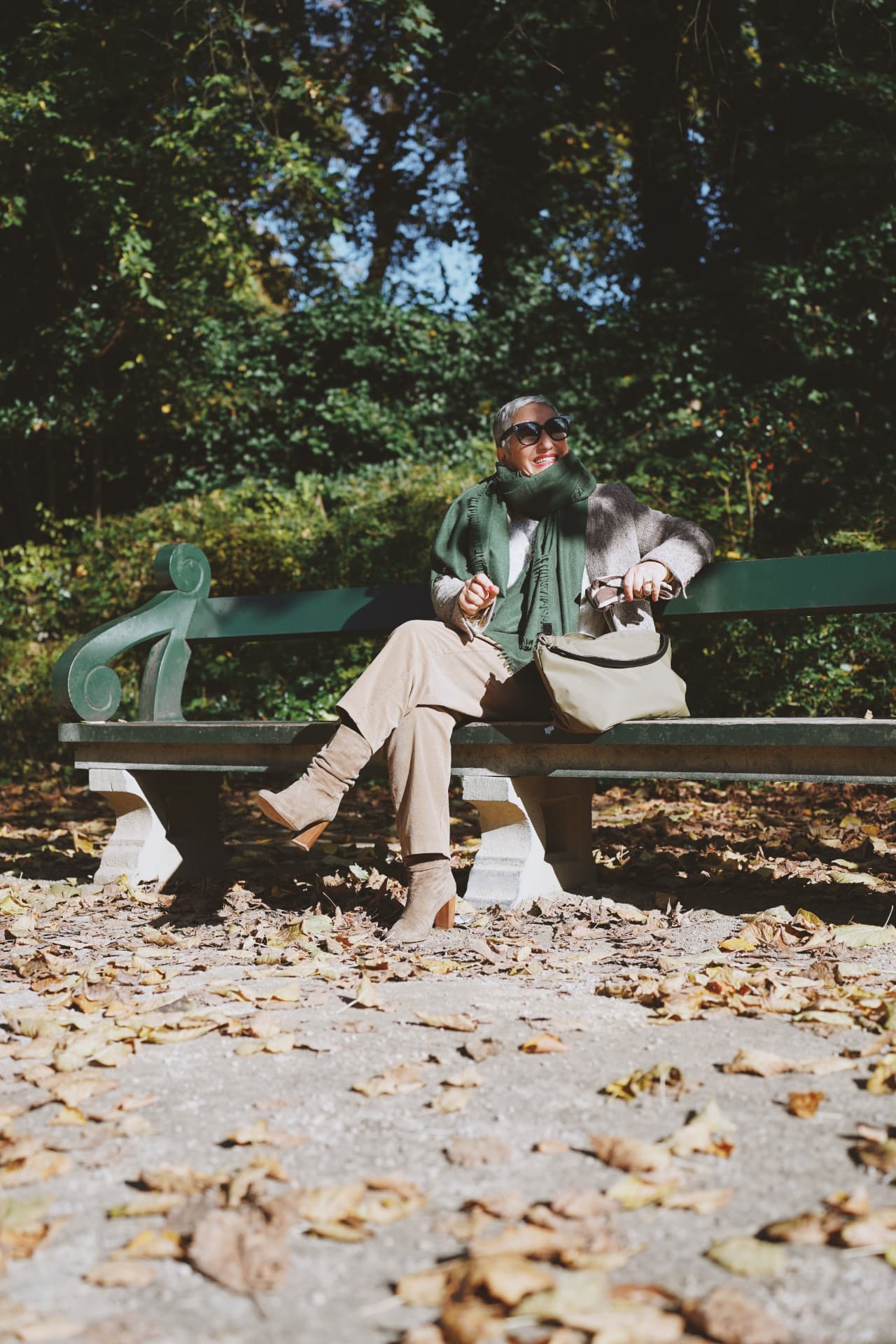 Assise sur un banc vert, écharpe verte et sac kaki