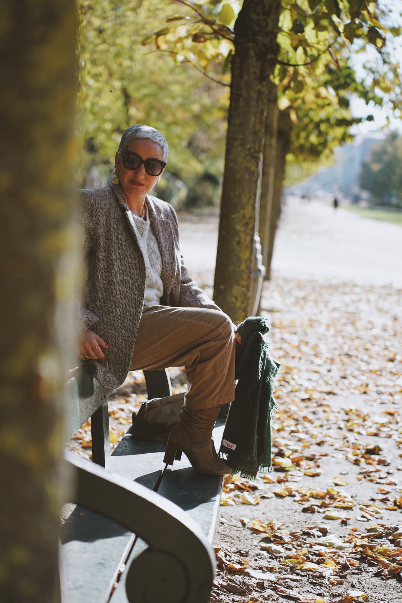 Sur un banc de l'allée, blazer en tweed, bottes et plaid vert