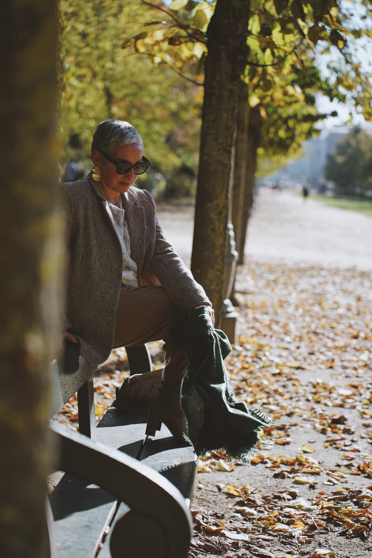Assise dans l'allée bordée d'arbres, blazer en tweed