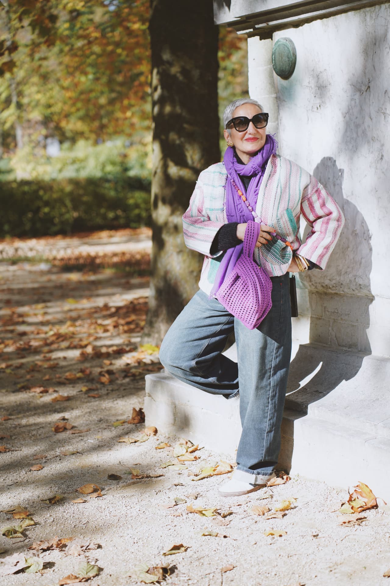 Adossée à la colonne, gilet rayé pastel et sac au crochet violet