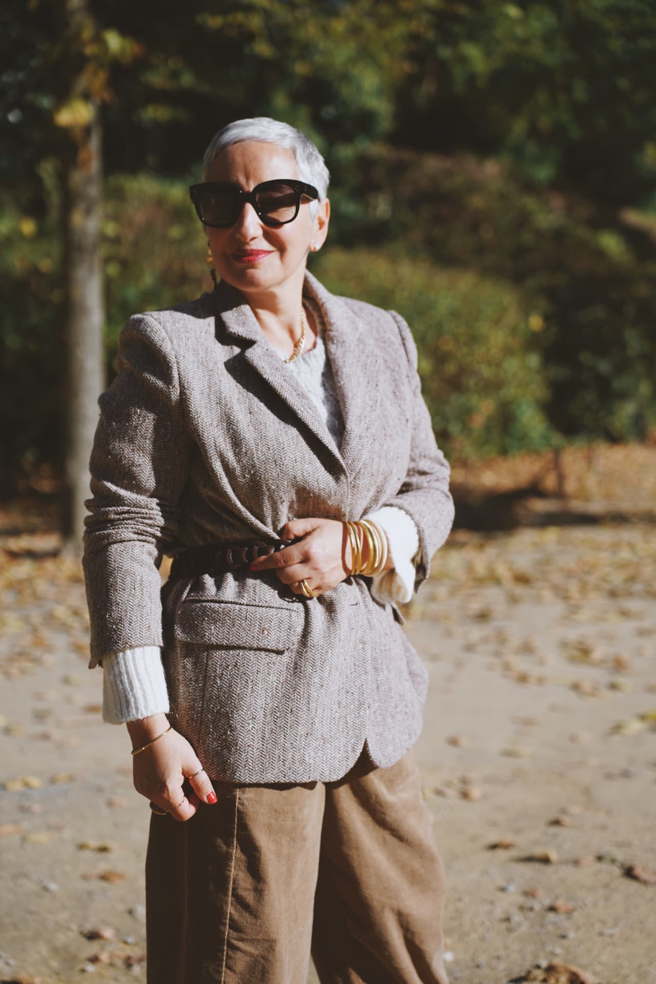 Portrait debout, blazer en chevrons ceinturé et bracelets dorés