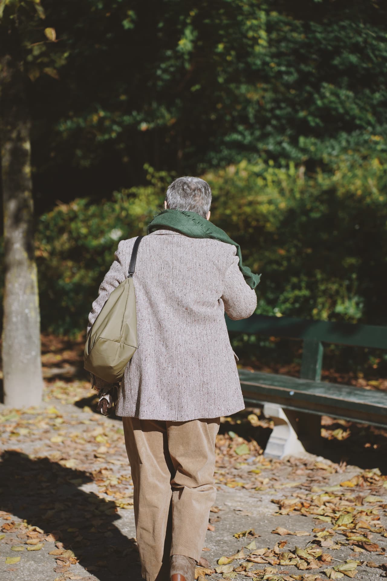 De dos dans l'allée, blazer en tweed, écharpe verte et sac kaki