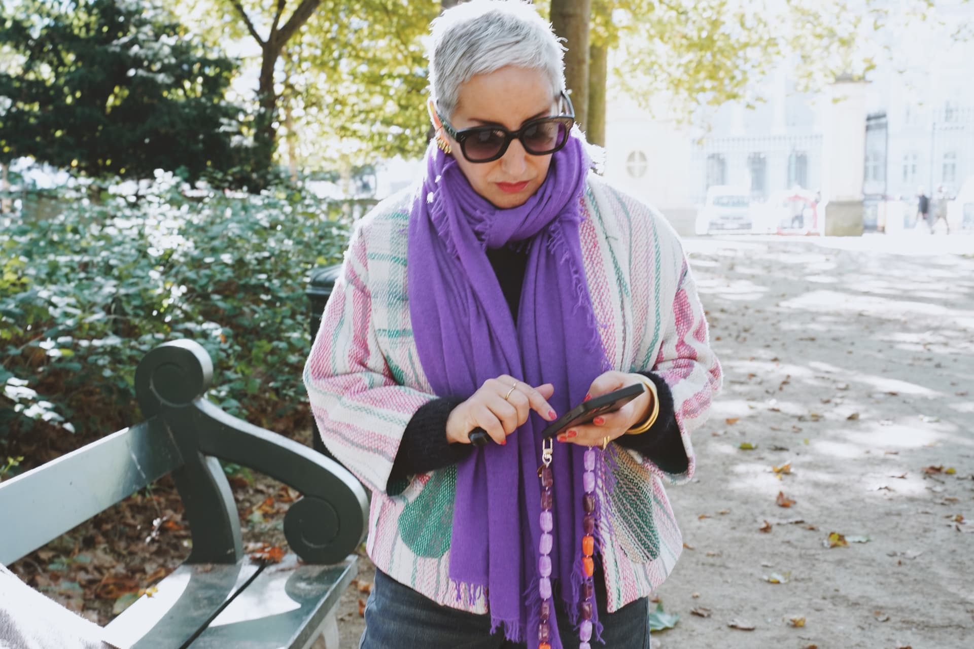 Écharpe violette et poncho tissé, téléphone à la main
