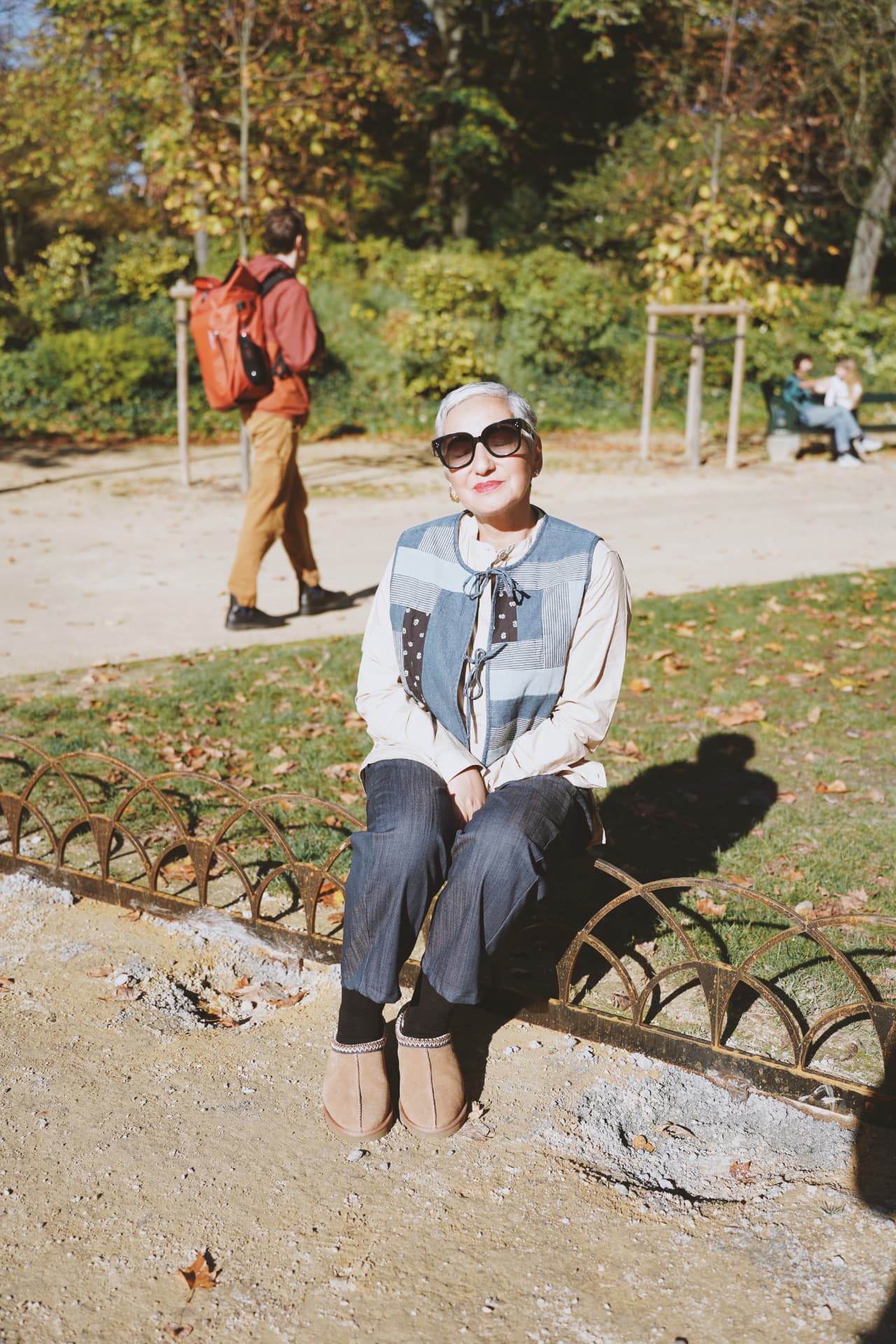 Assise sur la bordure du parterre, gilet patchwork denim et bottines