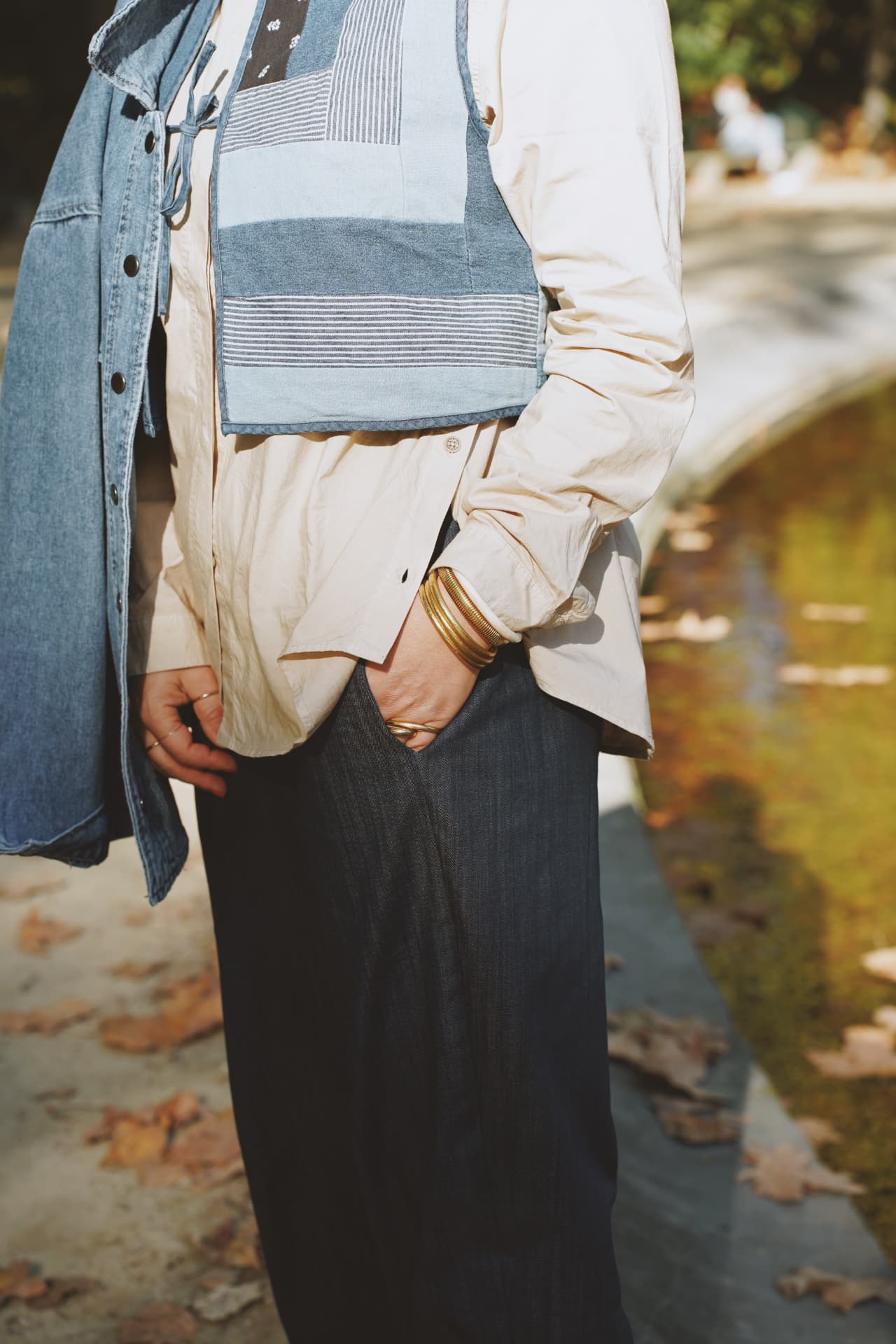 Détail : gilet patchwork en denim et bracelets dorés