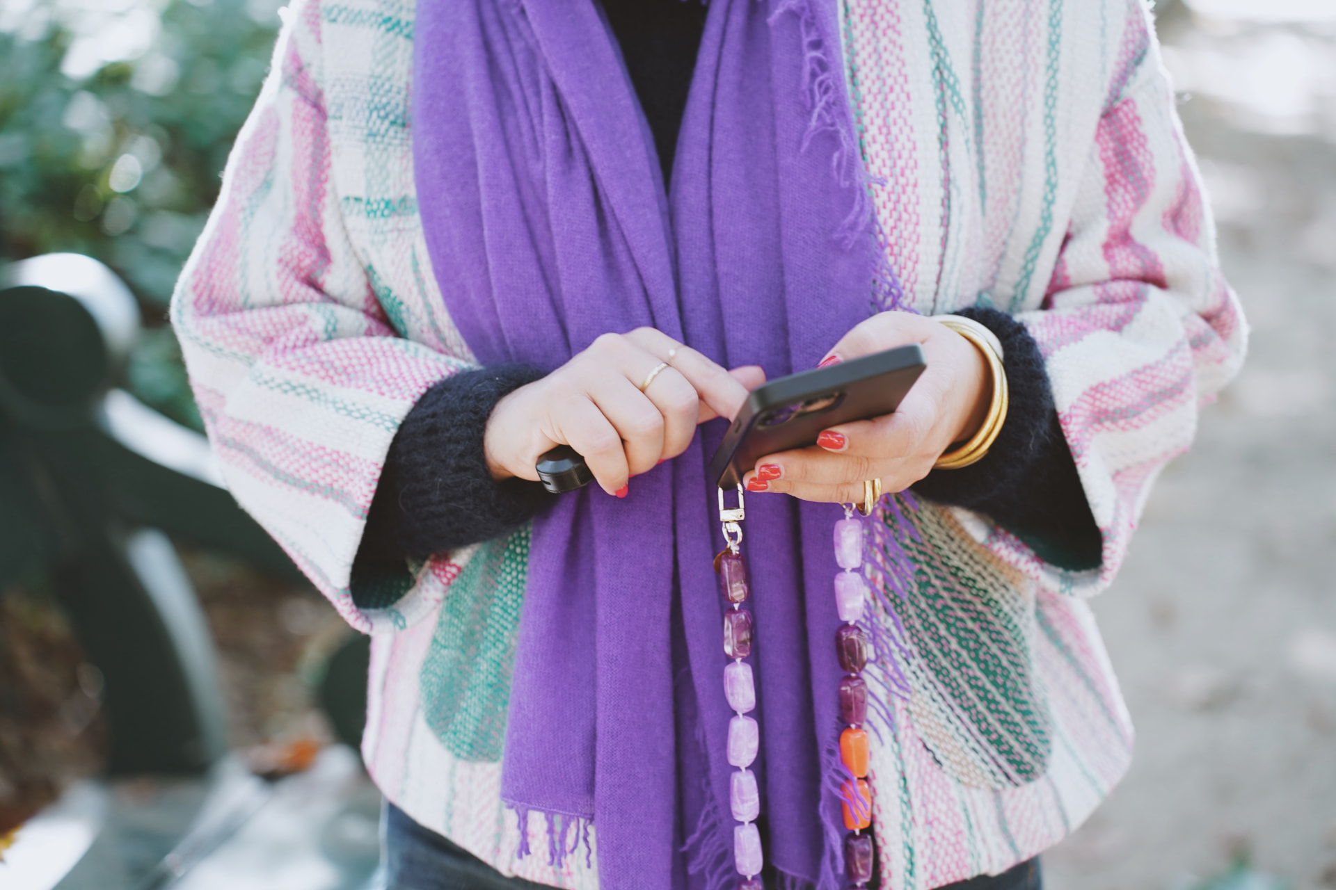 Détail des mains, téléphone, bijoux dorés et écharpe violette