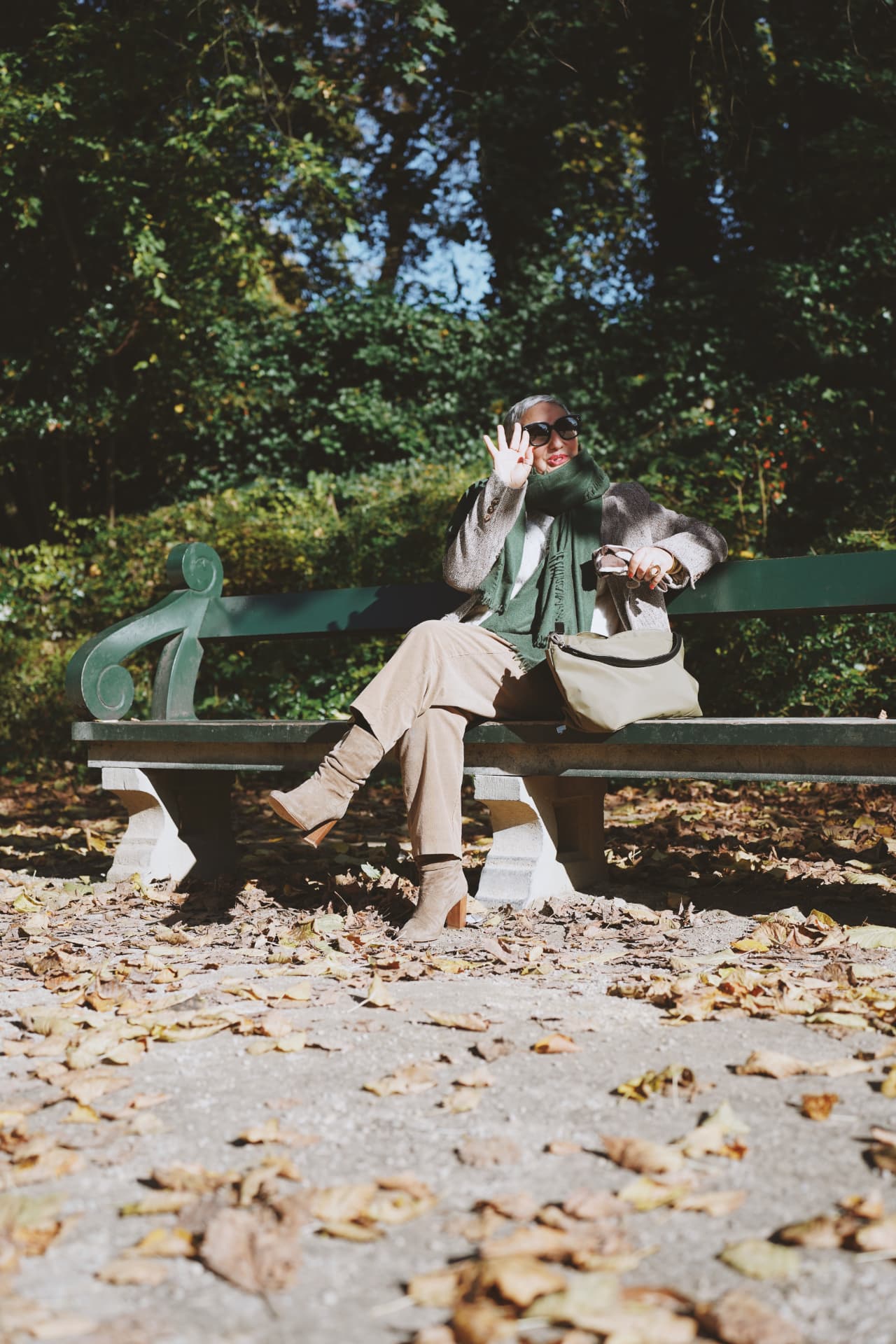 Sur un banc vert, écharpe verte et bottes en daim