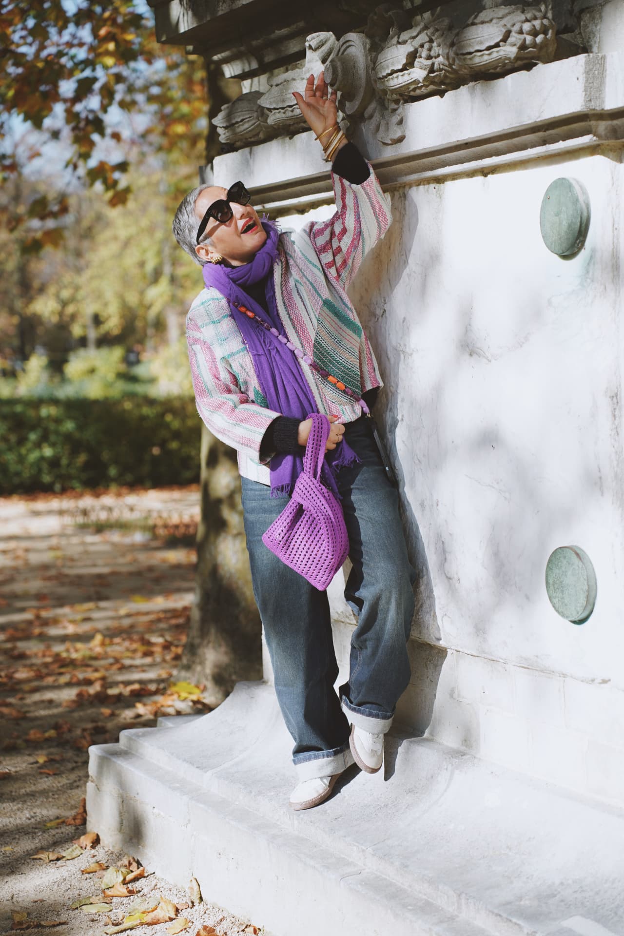Sur les marches, main levée contre la pierre, écharpe violette