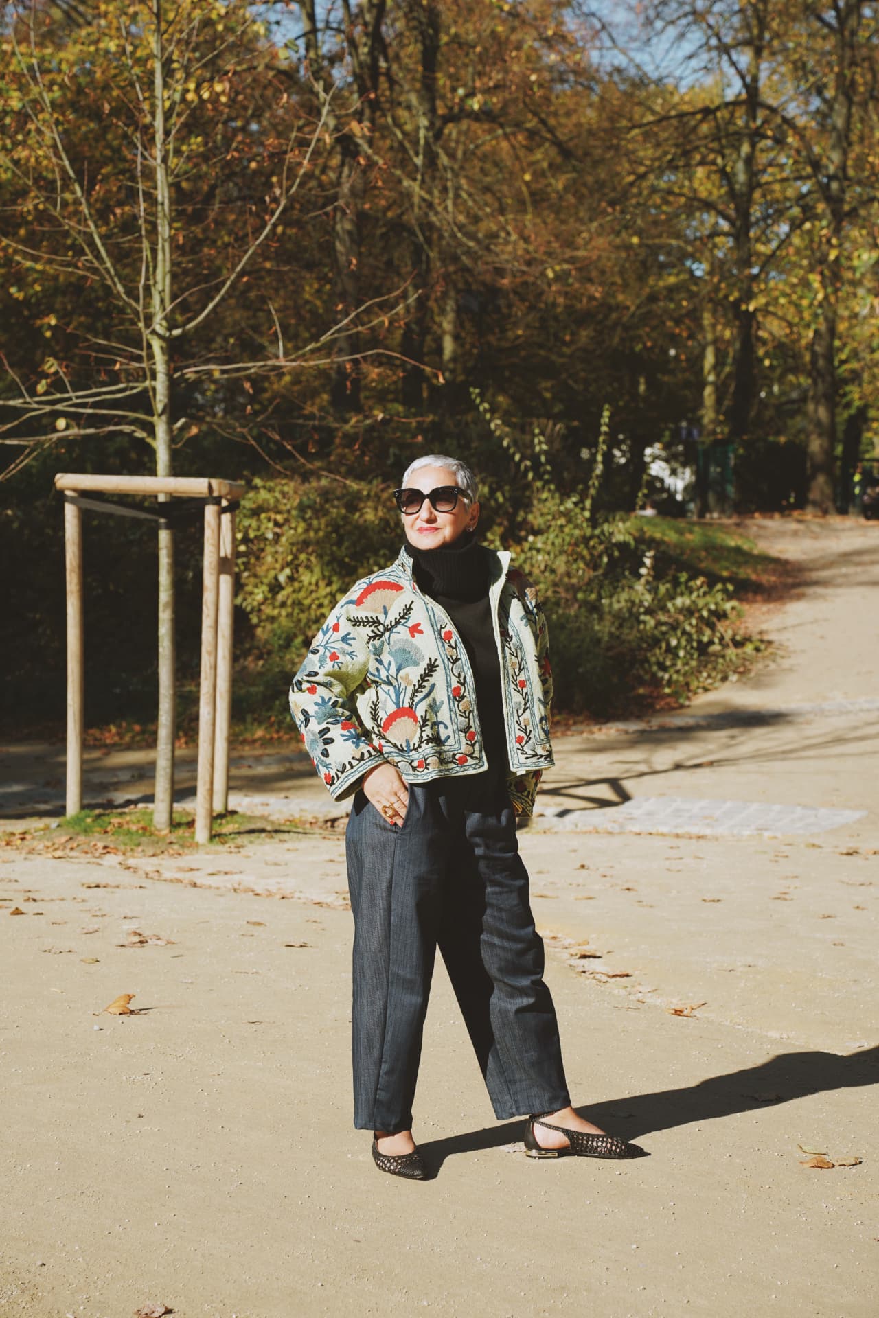 Debout dans l'allée, veste brodée florale et pantalon gris