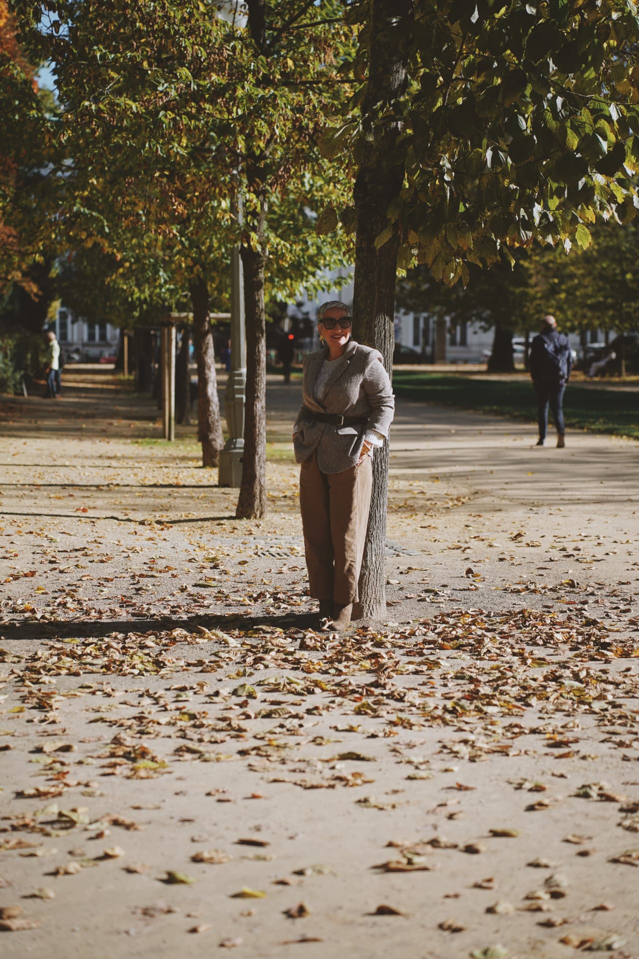 Adossée à un arbre, blazer ceinturé et pantalon camel